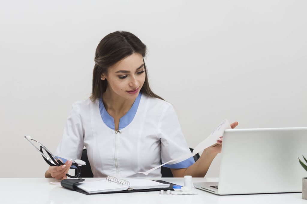 Imagem de médica sentada a mesa analisando documentos